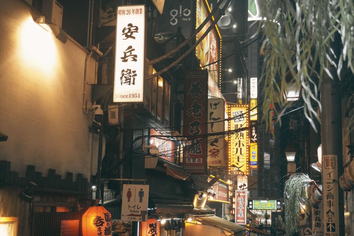 A busy Tokyo street at night lined with illuminated signage